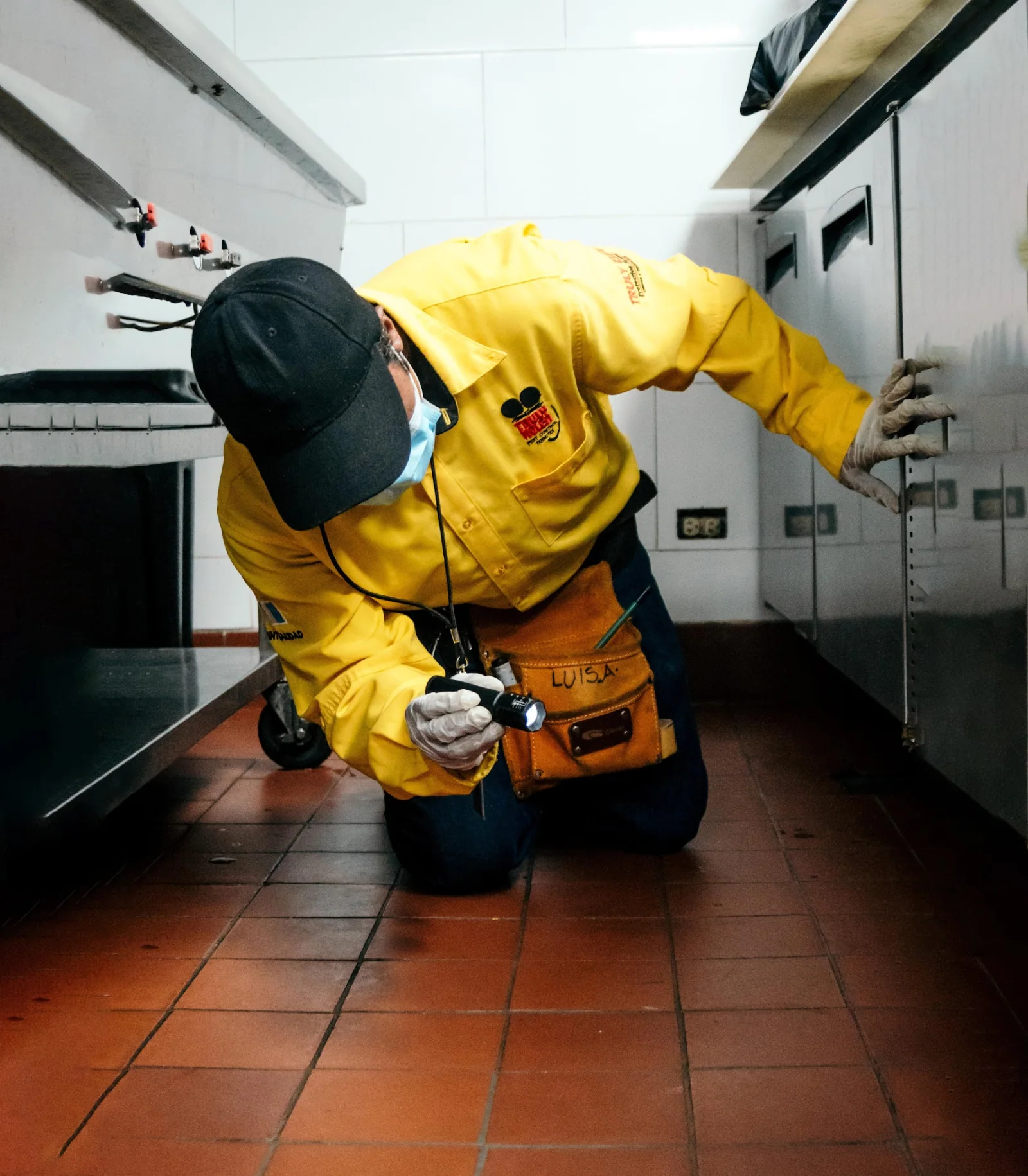 Técnico de Truly Nolen Guatemala trabajando en el área inferior de una cocina